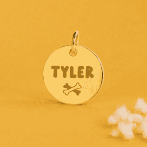Pendentif rond en or avec le nom Tyler et une patte de chien.